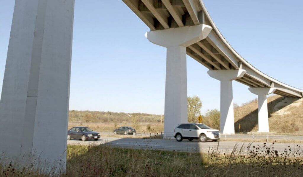 Tall interchange bridge over interstate with vehicles travelling underneath.